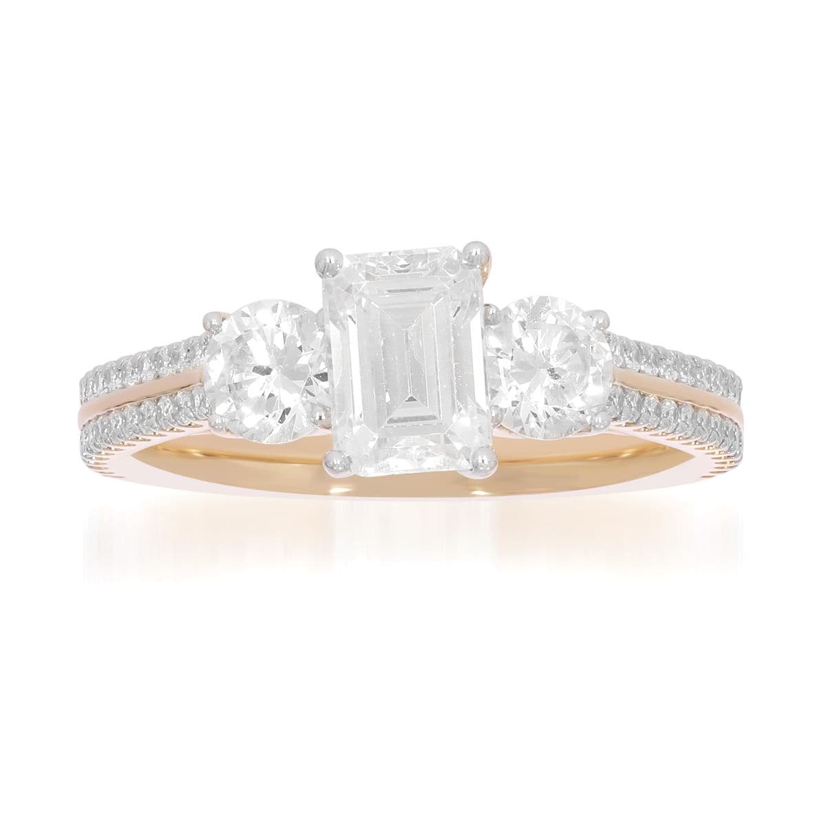A three stone ring with an emerald cut centre, in two-tone gold