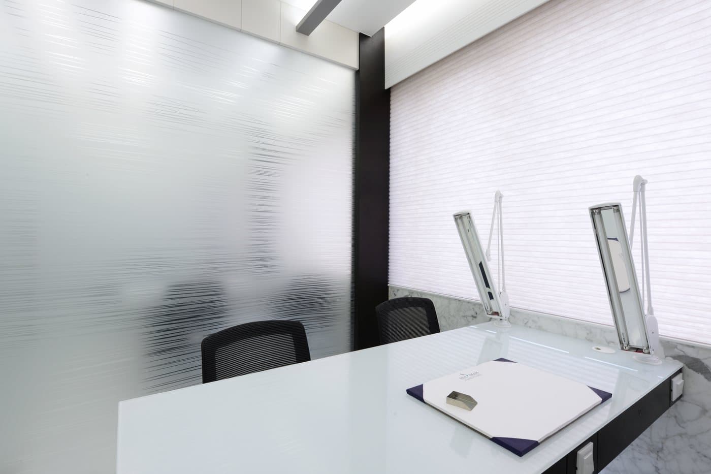 A grading desk with two daylight lamps beside a ribbed glass partition