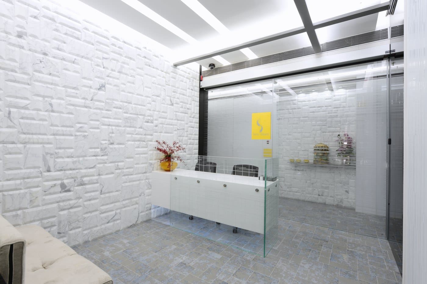 The reception with its white brick wall, glass screen and the S mark in yellow